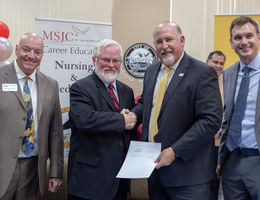 Dr. Carter and Dr. Schultz shake hands after signing the agreement