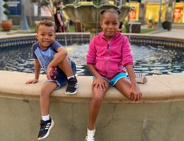 Young Black girl and boy sitting on a fountain edge