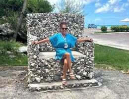 Brenda Roper sits on cobblestone throne or chair in a blue dress and sunglasses