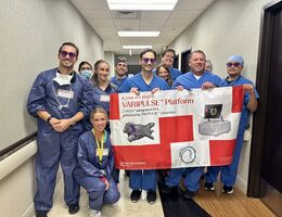 Cardiology team stand together in a hallway holding a large banner that reads “VARIPULSE Platform.” 