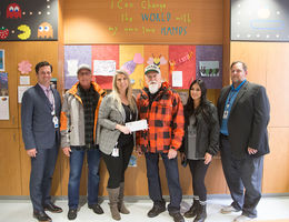 two male hospital administrators, one female Children's Hospital foundation representative, and three people from Quaid Harley-Davidson pose for photo with check