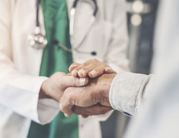 unidentified doctor holds hand of unidentified patient