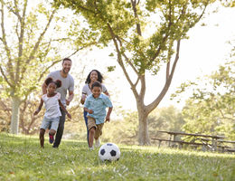 Family Playing Soccer In Park Together