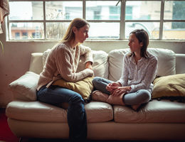 mother and daughter sitting on couch having a talk