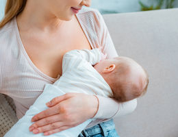cropped shot of young woman breastfeeding infant baby at home