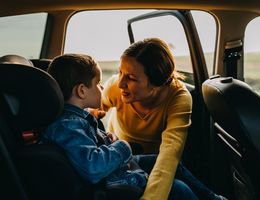 Mother talking to son in back of the car as she fixes car seat