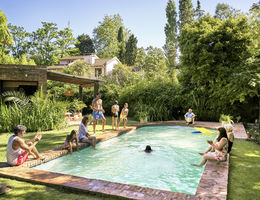 Wide angle view of multi-generation family relaxing and watching children play and swim in backyard pool