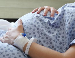 pregnant women in hospital gown holding baby