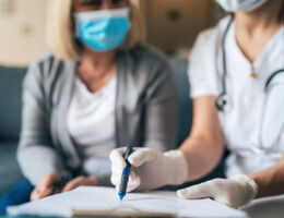 physician sits with patient using clipboard 