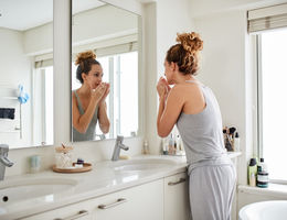 Woman smelling her breath while looking in the mirror 