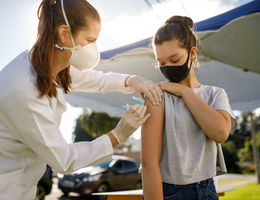 female physician vaccinates teenage girl