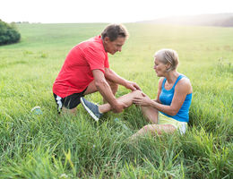 Male helping female with knee pain while hiking