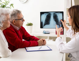 Physician showing older couple x-rays of lungs