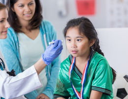 Young girl at the doctor's office with her mother. Doctor is examining her eyes following a hit.
