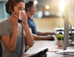 Female sneezing into napkin at her desk.