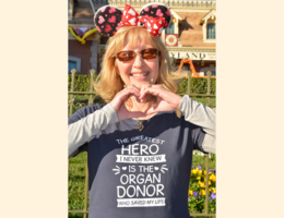 Julie Hutchinson makes a heart with her hands while wearing an organ donor appreciation shirt