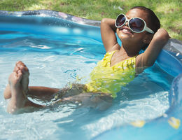 Hispanic girl relaxing in kiddie pool 
