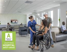 Woman in wheelchair, speaking to clinician in scrubs at a hospital