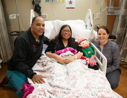 doctor poses with patient mom and medical staffer