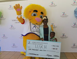 Mascot, Alyssa Jean-Marie, and Ashton hold the donation check