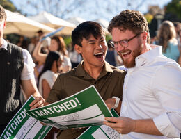 Asian man and Caucasian man outside smiling as they learned their fate at match day 2026