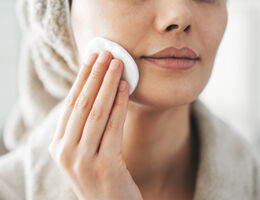 Woman swiping cotton pad across skin