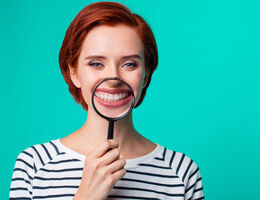 Woman holding a magnifying glass in front of teeth