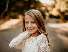 young blond girl smiling widely at the camera in outdoor photo