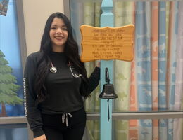 Heather Kono stands by cancer free bell on pediatric cacner unit