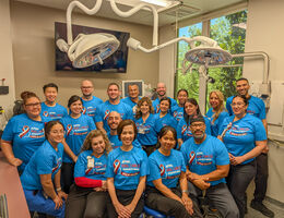 A group of people in blue shirts stand together in a dental office