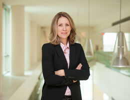 Rhonda Spencer-Hwang, DrPH, MPH standing inside the hospital with her arms crossed