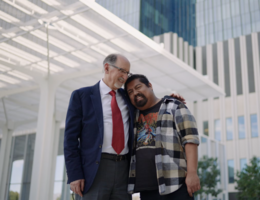 a man in a suit is hugging another man while smiling