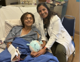 Patient Jesse Campos smiles while on hospital bed next to Dr. Tanya Minasian