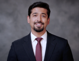 A man in a suit with a beard is smiling