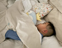 Young boy sleeping while tucked under blanket