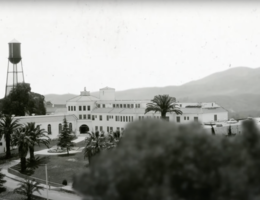 black and white photo of a university campus, hills in the background, trees in the foreground