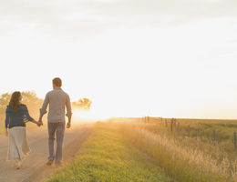 Couple walking toward a sunset on a dirt road