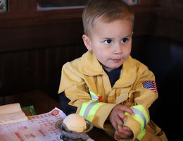 This young spaghetti fan enjoyed being served by firefighters during Tip-A-Firefighter during the dinner shift on Wednesday, May 30. boy in a firefighter uniform