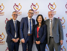 From left, Daniel Dawes, Anthony Hilliard, Helen Tran and Richard Hart standing in front of a backdrop showcasing the HEART initiative graphic