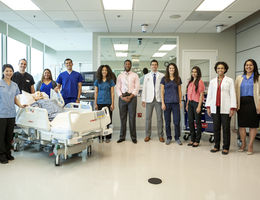 Loma Linda University staff of nurses, physicians and faculty stand in the middle of a patient's room. 