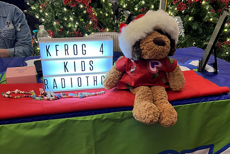 Dog in santa hat next to sign that says "KRFOG 4 Kids Radiothon"