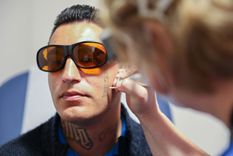 Dr. Burruss uses a laser to remove a tattoo on David Loya's face