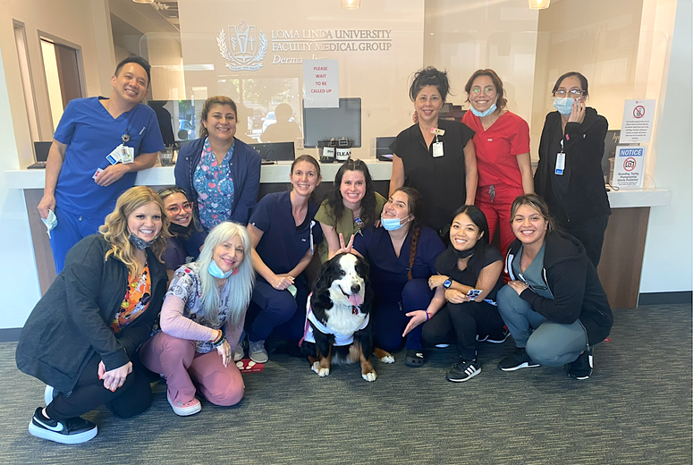 Emma the therapy dog surrounded by the surgical dermatology staff for a photo with everyone smiling