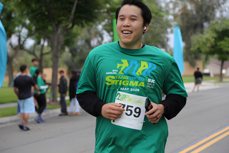 Participant running in green “Stand Up to Stigma” shirt with bib 759 on a road.