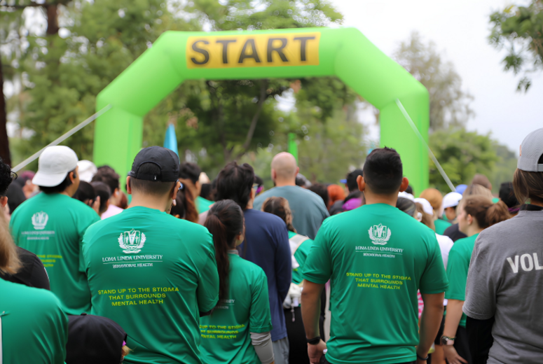 Participants in green shirts gather at a 5K start line under a green “START” arch.