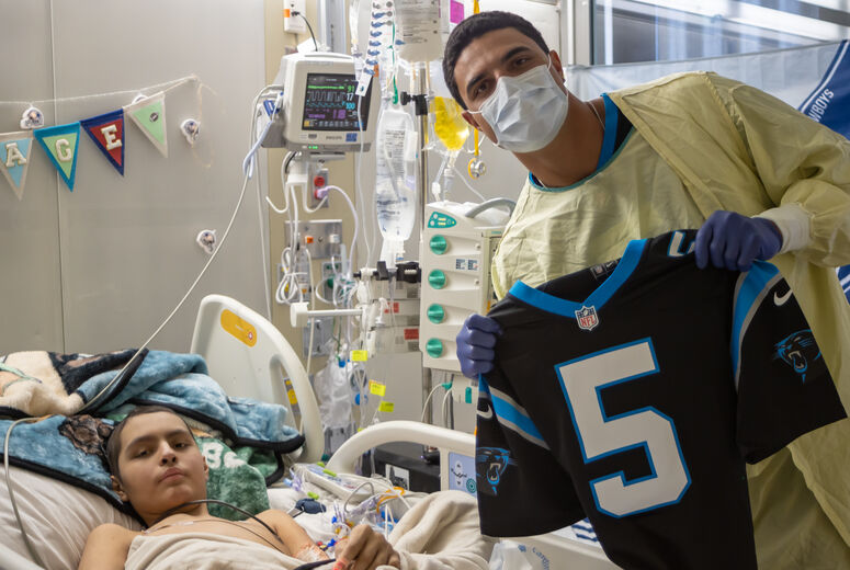 Jaelan poses with jersey beside young patient