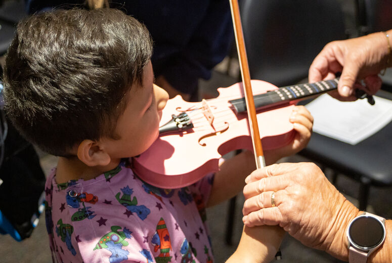 Woman helps young patient hold and play violin