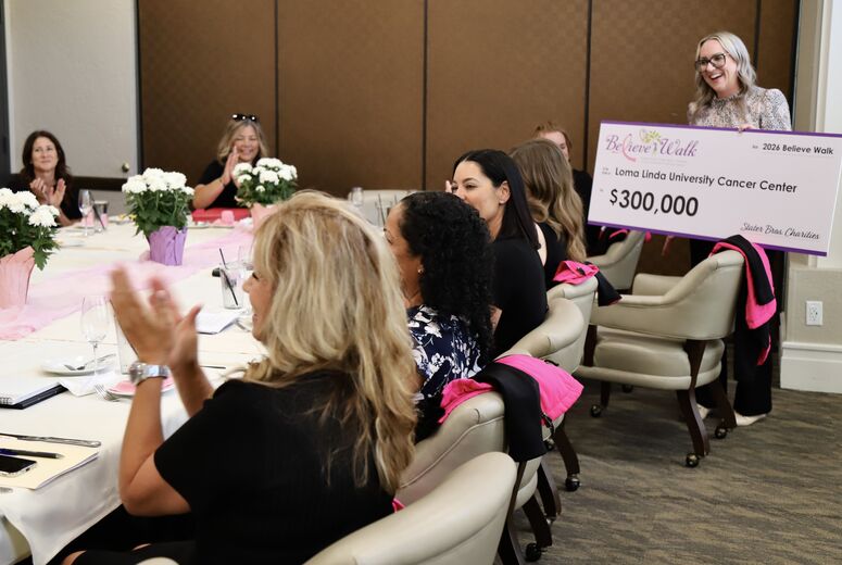 a woman holds a large check presenting to a group of people