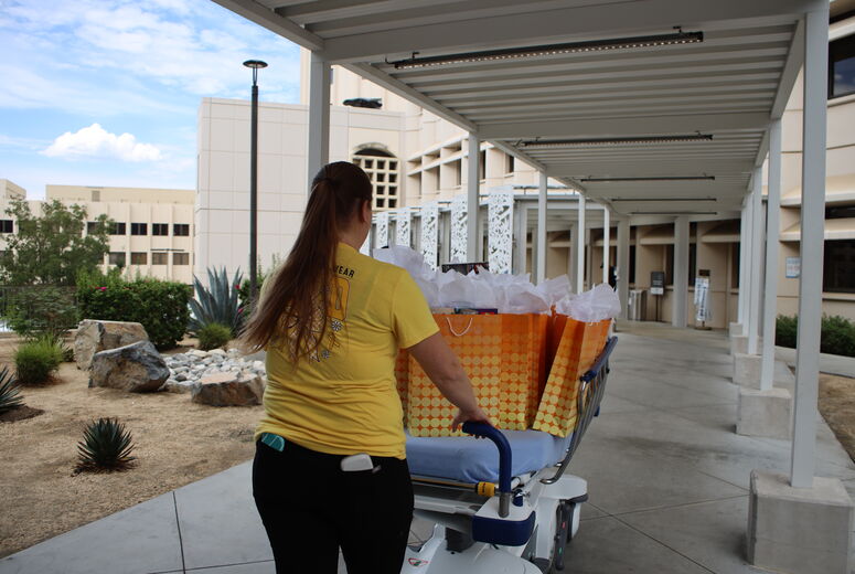 hospital worker rolls cart carrying gifts