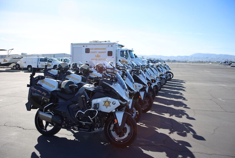 dozens of motorcyles and other police vehicles parked on tarmac